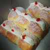 Fiji-style cream buns filled with whipped cream, dusted with icing sugar and topped with red cherries