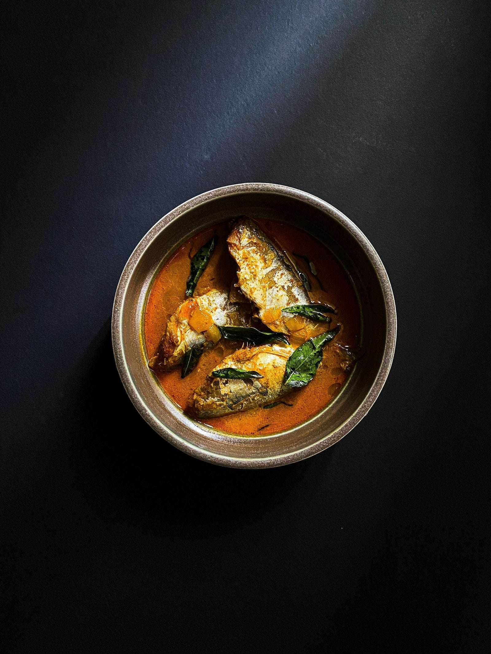 Thin curry served in a round stainless steel bowl